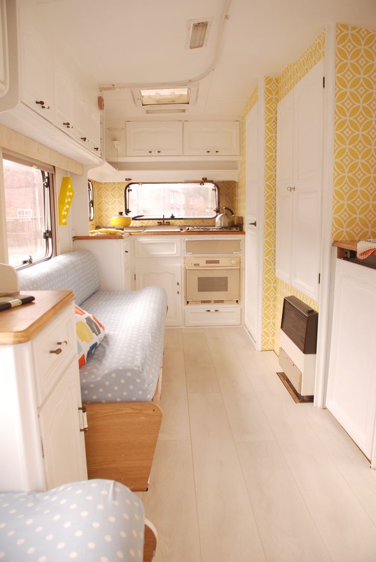 the interior of a camper with two beds and a kitchen in the back ground