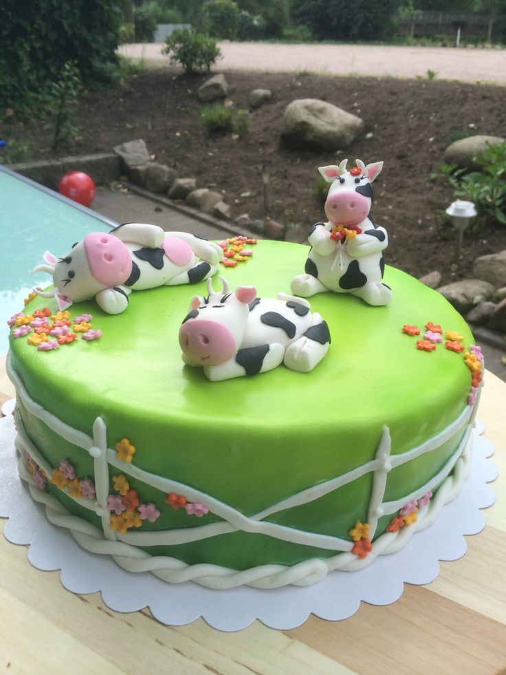 a green cake decorated with cows and flowers