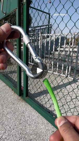 a hand holding a green toothbrush in front of a chain link fence