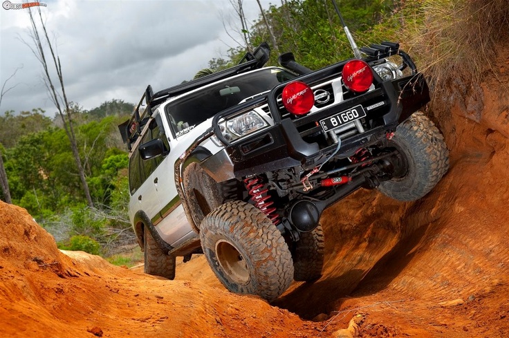 a white four - door truck driving on a dirt trail