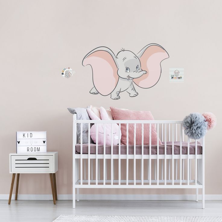 a baby's room with an elephant decal on the wall and a white crib