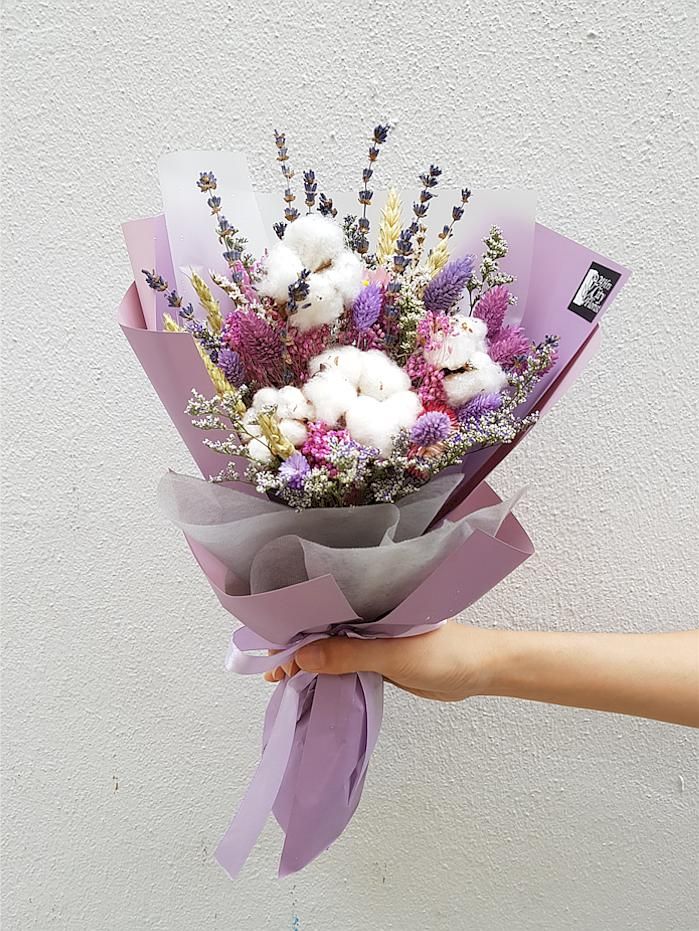 a person holding a bouquet of flowers in their left hand with purple ribbon around it