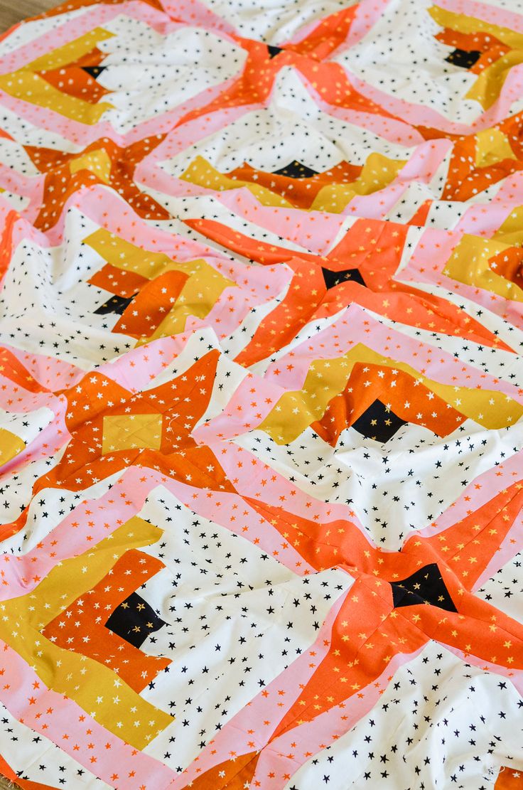 an orange and pink quilt with black dots on it