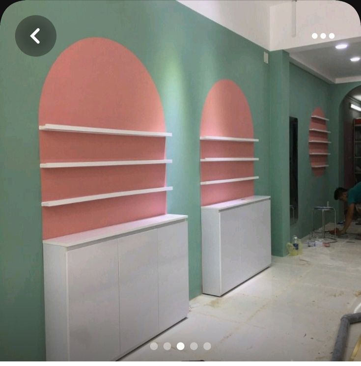 the room is being painted with pink and green walls, along with shelving units