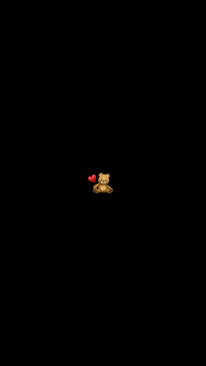 a teddy bear with a red heart in its mouth on a black background that appears to be dark