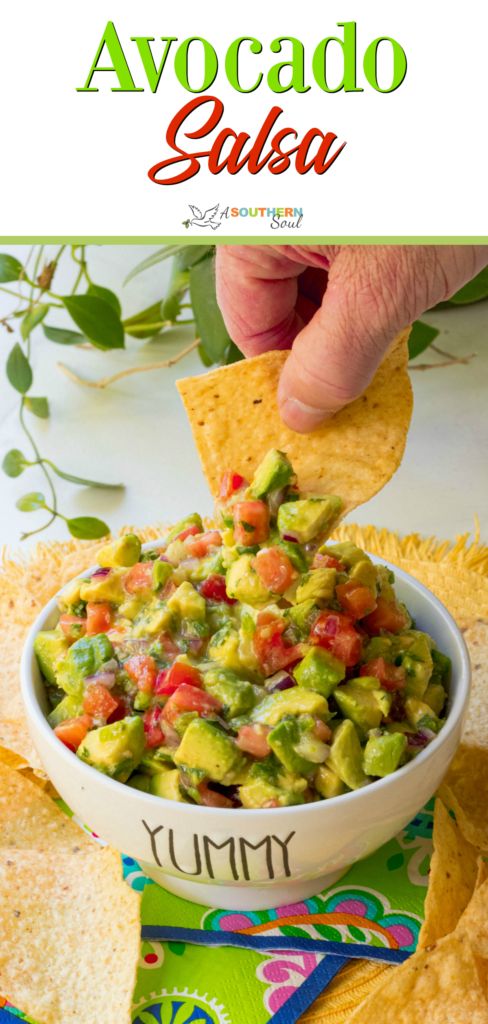 a person dipping guacamole into a bowl with tortilla chips on the side