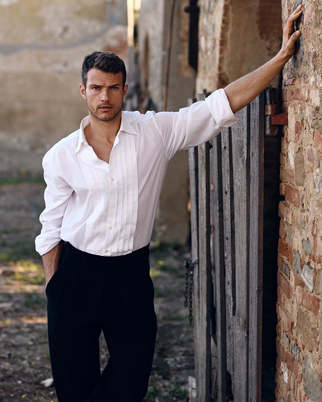 a man leaning against a brick wall with his hand on the side of the building