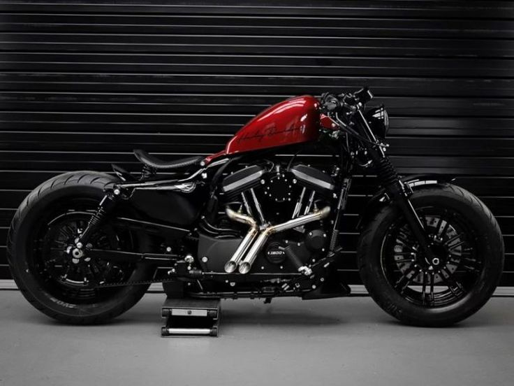 a red and black motorcycle parked in front of a garage door