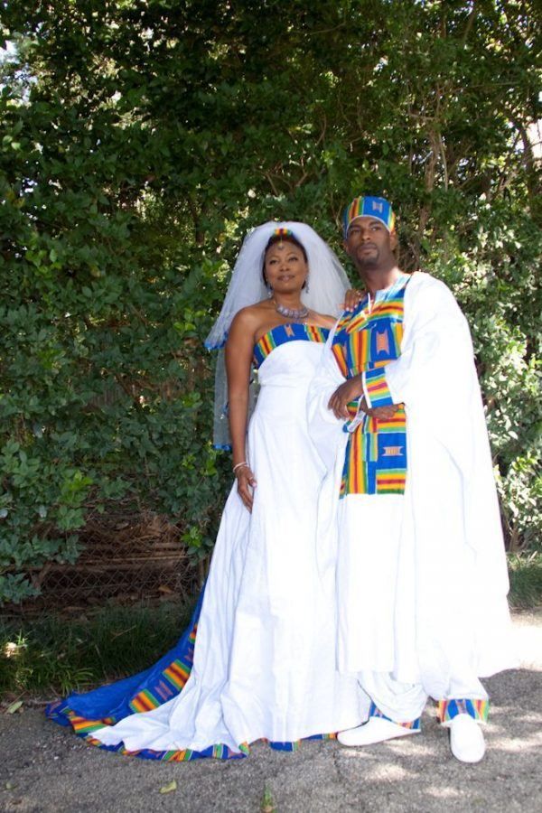 two people dressed in white and blue standing next to each other with trees behind them