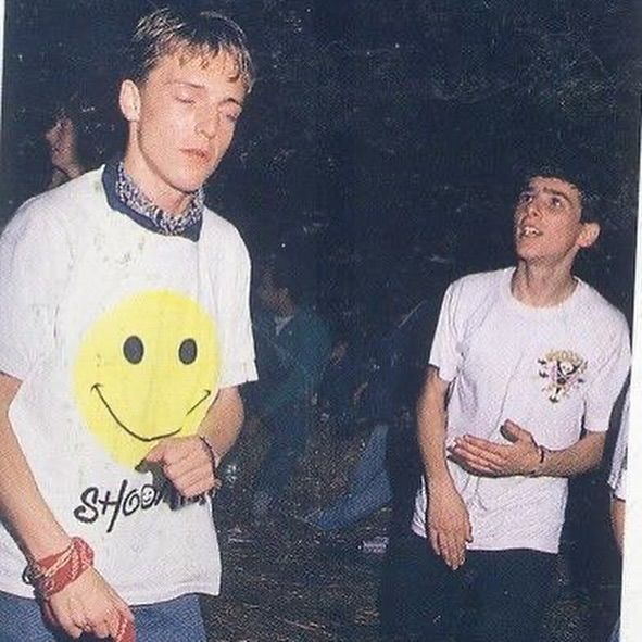 two young men standing next to each other with a smiley face on their t - shirt