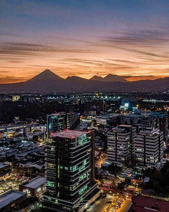 an aerial view of a city at night with mountains in the background