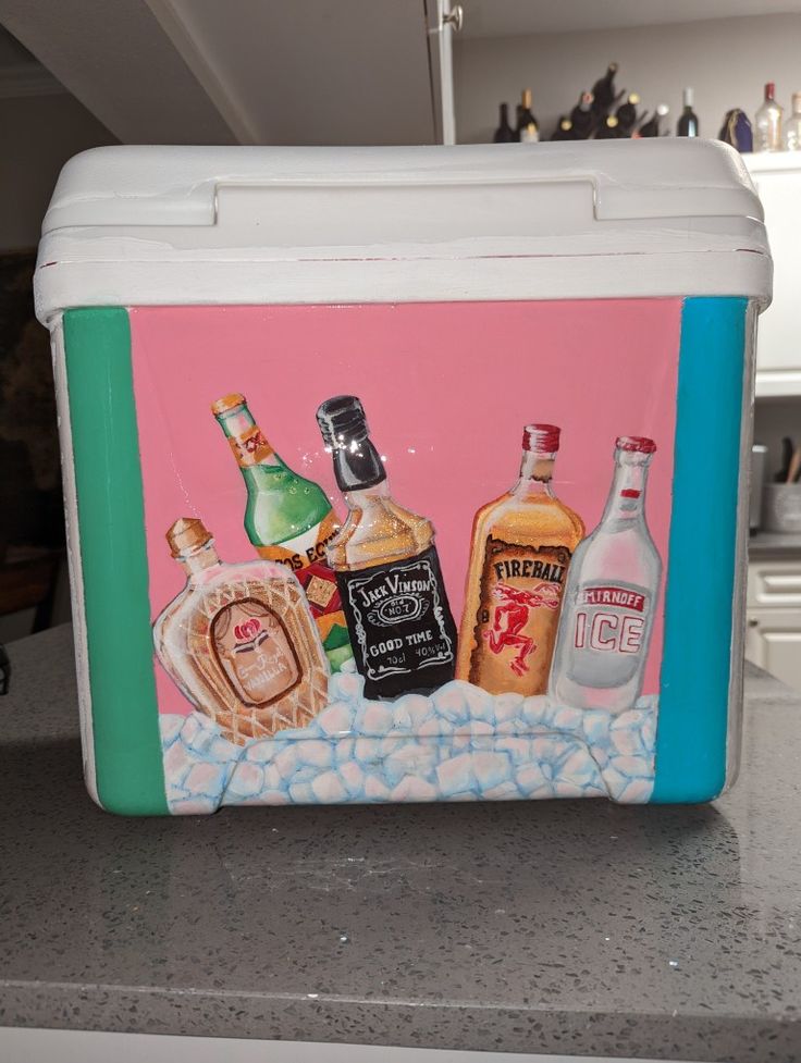 an ice chest painted with liquor bottles on the front and back, sitting on a countertop