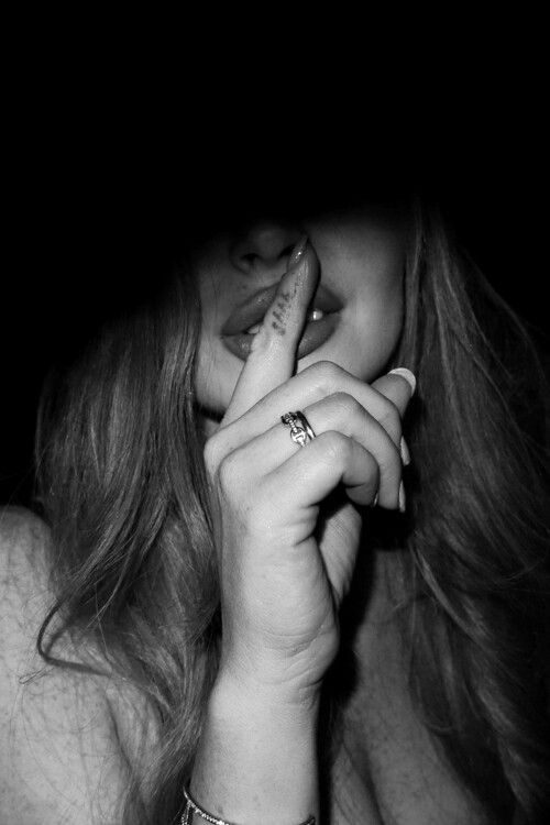 a woman with long red hair holding her hand up to her face in the dark