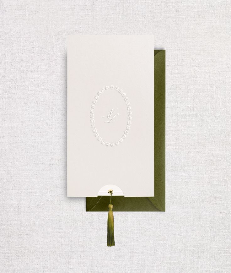 a white card with a green ribbon hanging from it's side on a wall