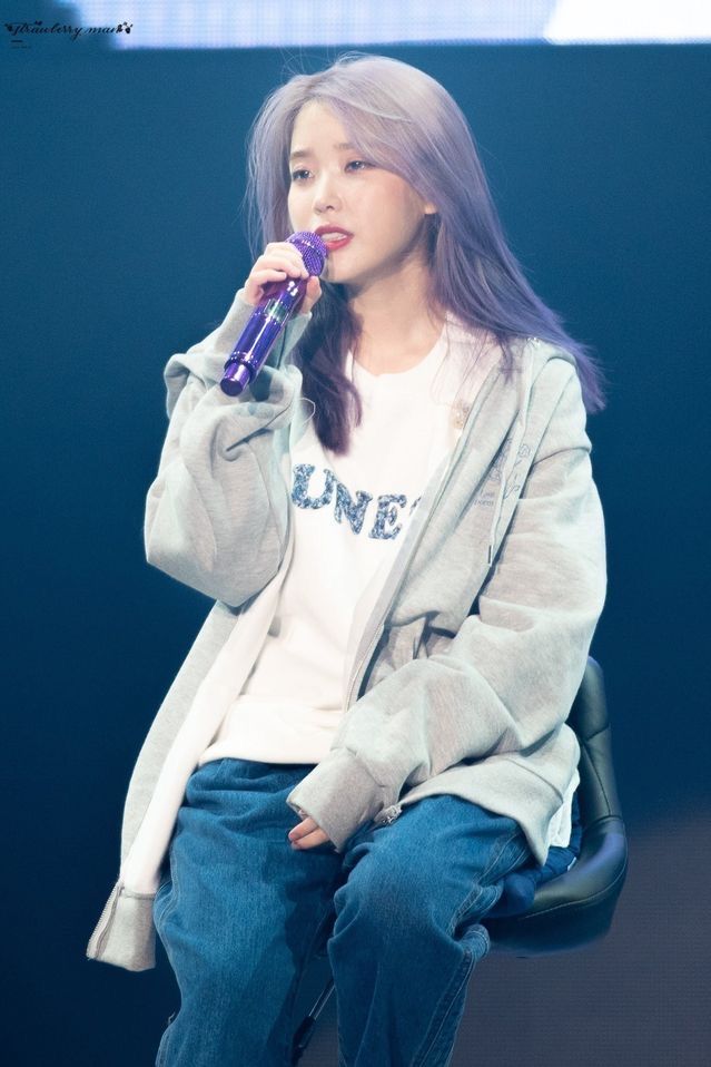 a woman sitting on top of a chair while holding a purple object in her hand