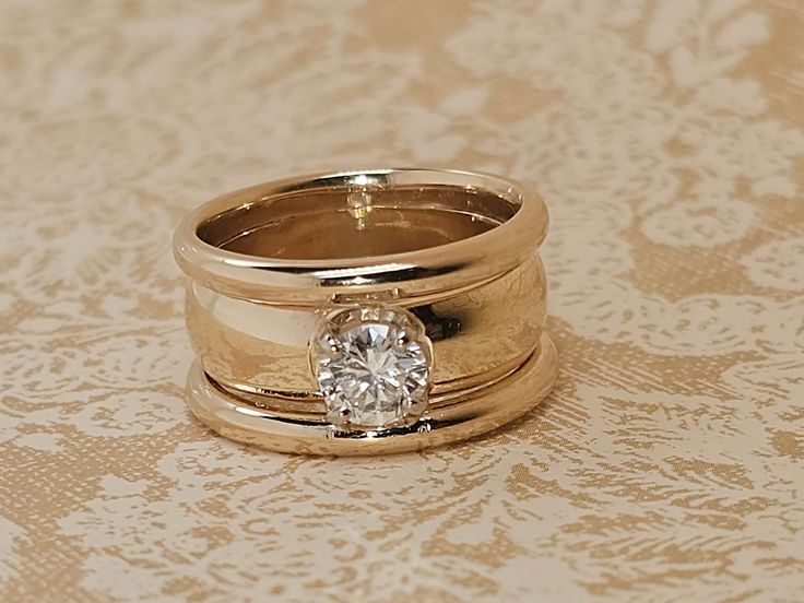 two gold wedding rings with a diamond on top