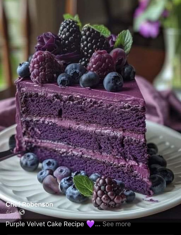 a purple velvet cake with blueberries and raspberries on top is sitting on a white plate