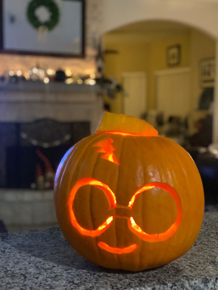 an orange pumpkin with glasses carved into it's face on top of a counter