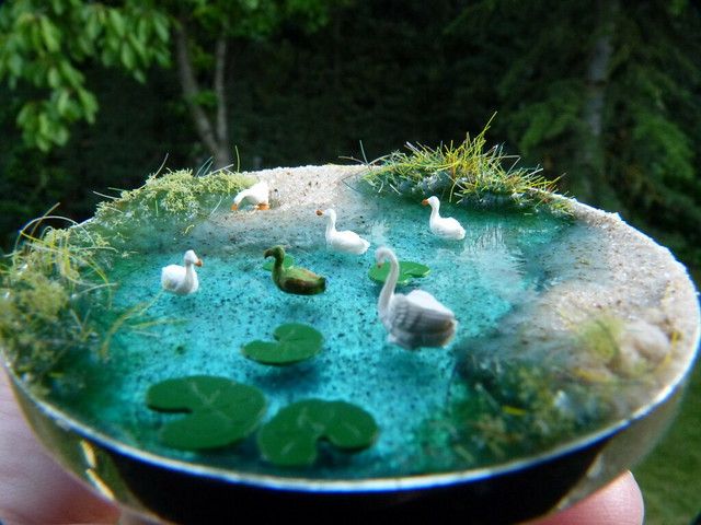 there is a bowl with water and birds in the pond on it that has lily pads