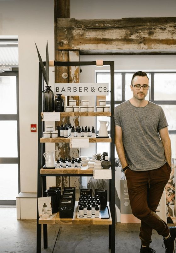 a man standing in front of a shelf with bottles and other items on it's shelves