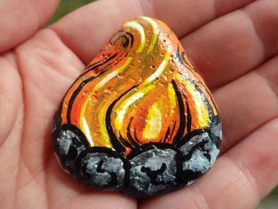 a hand holding a small orange and black rock