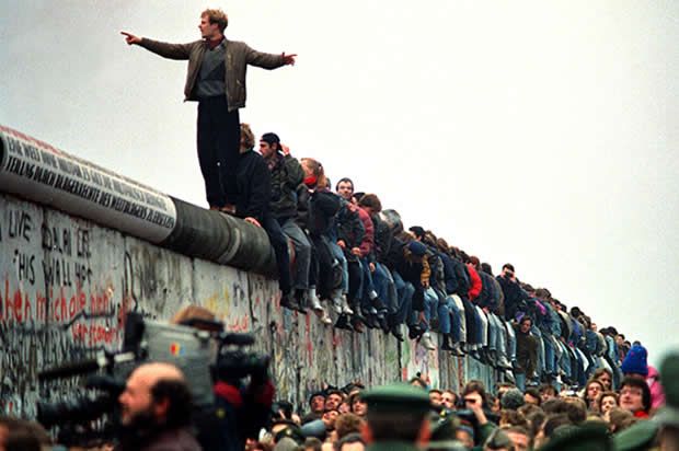 a man standing on top of a wall next to a bunch of people in front of him