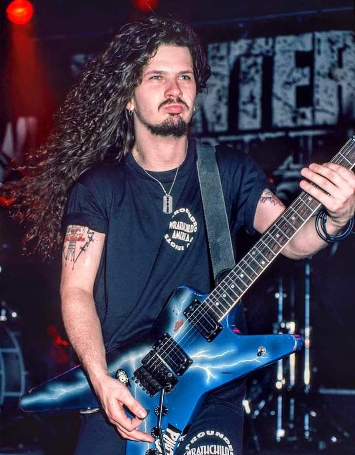 a man with long hair holding a blue guitar