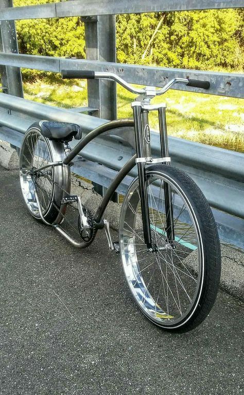 a bicycle parked on the side of a road next to a wooden fence and grass