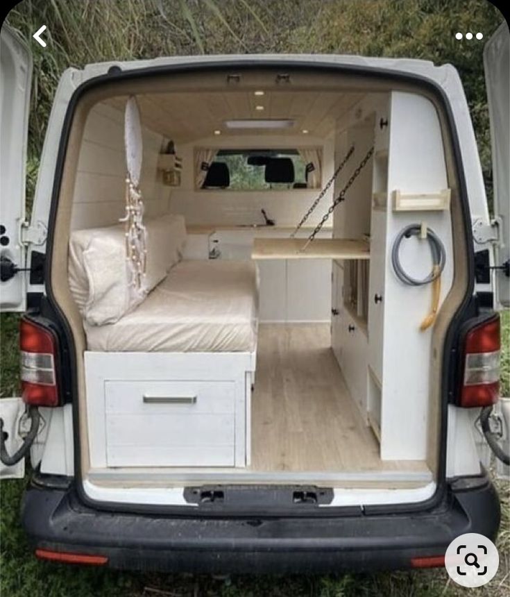 the back end of a white van with its bed pulled up to it's side