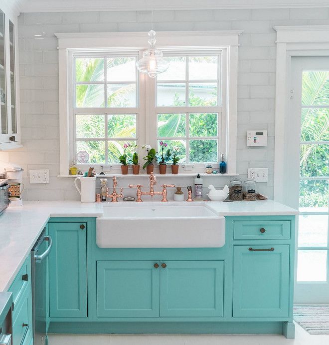 a kitchen with blue cabinets and white counter tops, an island style sink and dishwasher