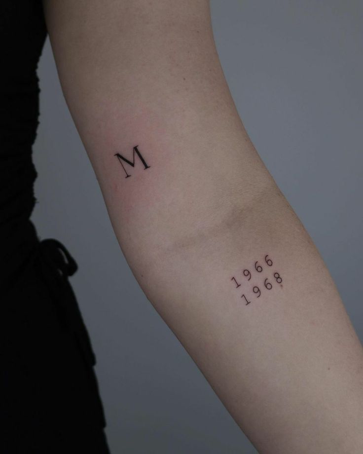 a woman's arm with the letter m tattooed on it