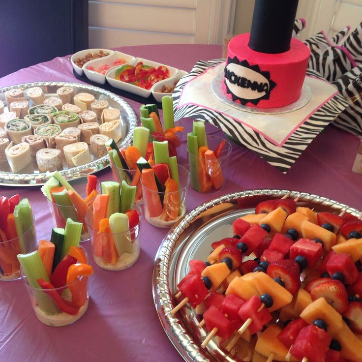 a table topped with lots of food on top of a purple cloth covered tablecloth