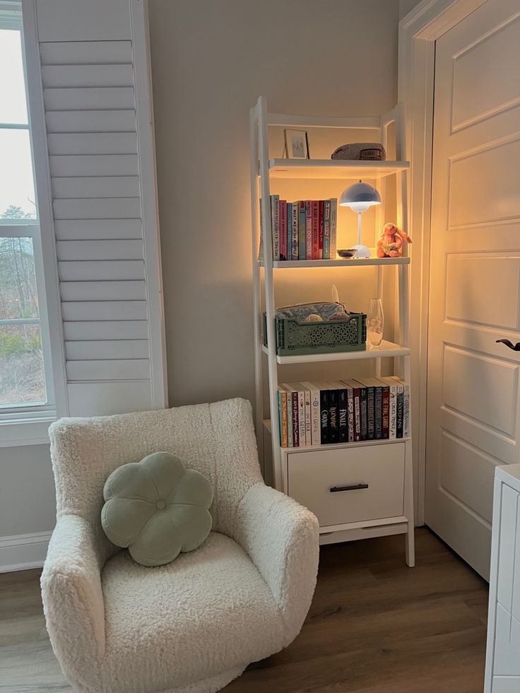 a white chair sitting next to a book shelf filled with books