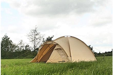 a tent pitched up in the grass on a cloudy day