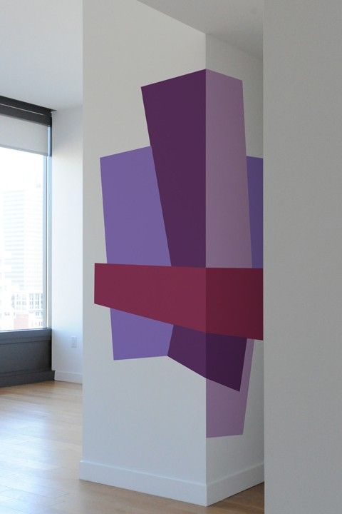 an empty room with purple and pink squares on the wall, next to a window