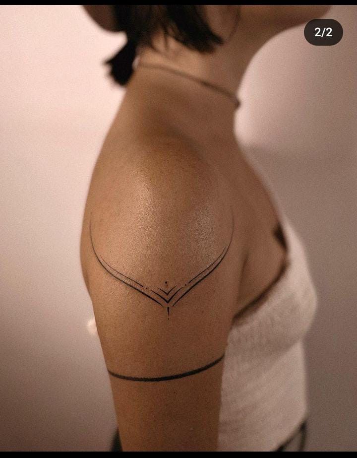 the back of a woman's shoulder with an arrow tattoo on it