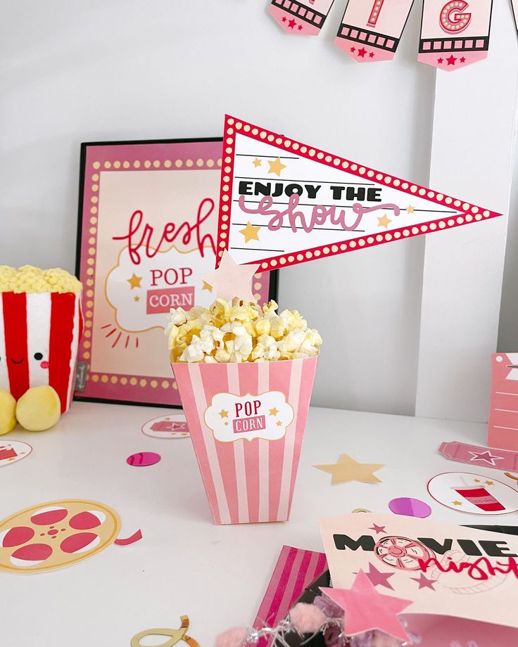 a popcorn bucket filled with popcorn next to other party supplies and decorations on a table