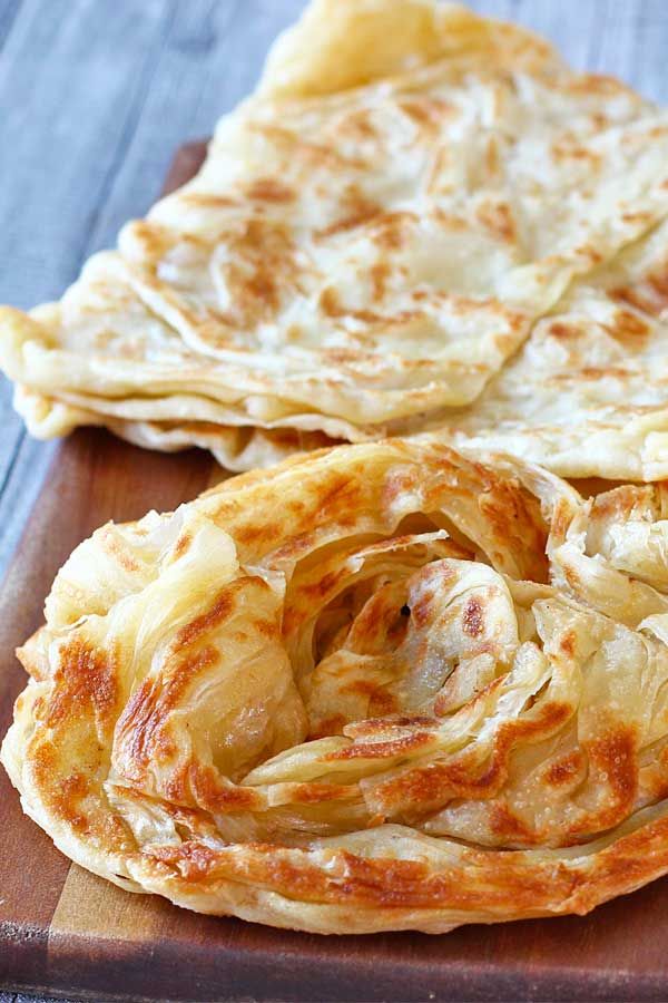 two flat breads sitting on top of a wooden cutting board next to each other