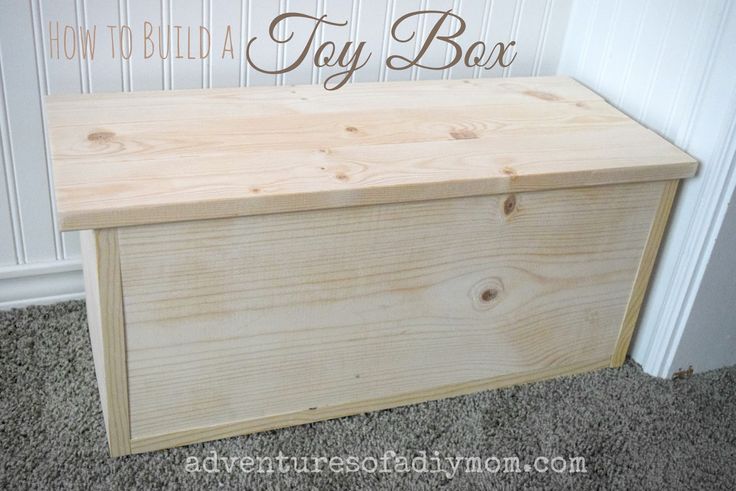 a wooden toy box sitting on the floor in front of a wall with words how to build a toy box