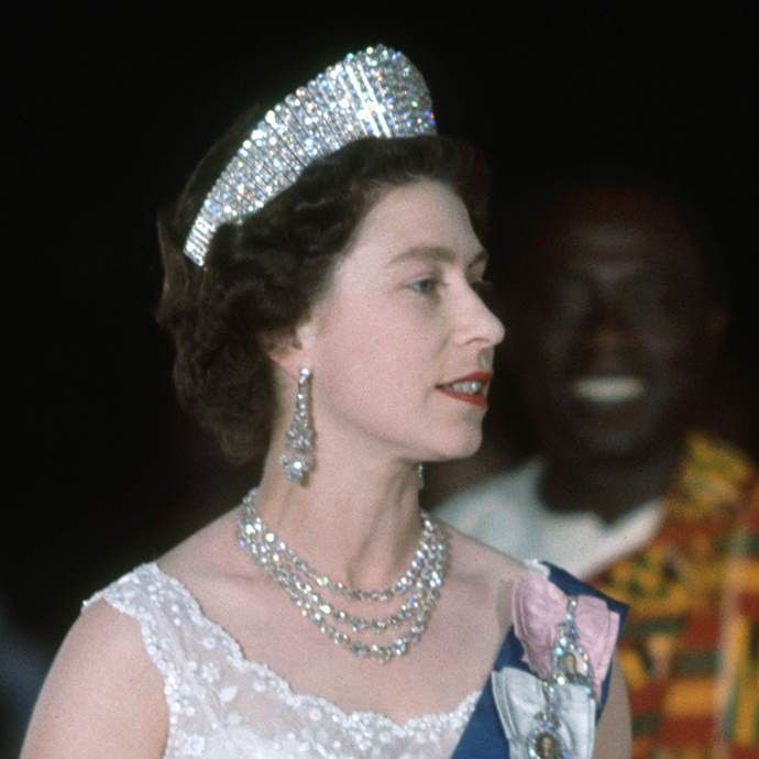 queen elizabeth of england wearing the tiara and diamond necklace, with other people in uniform behind her