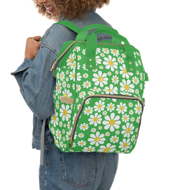 a woman wearing a green backpack with white daisies on the front and back pockets