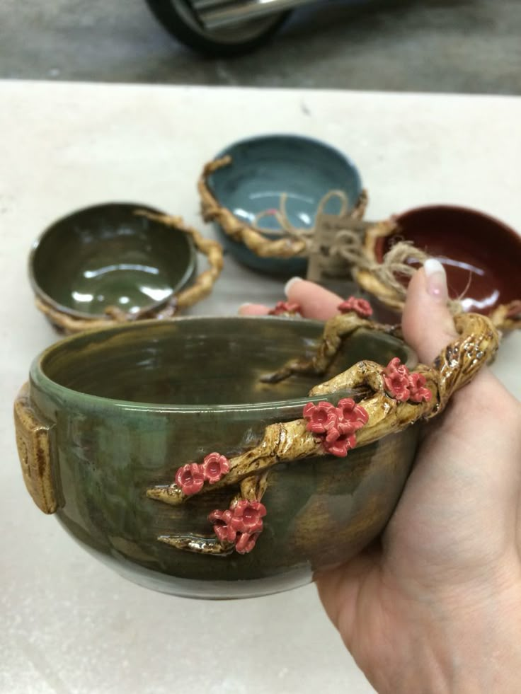 a person is holding a bowl with flowers on it