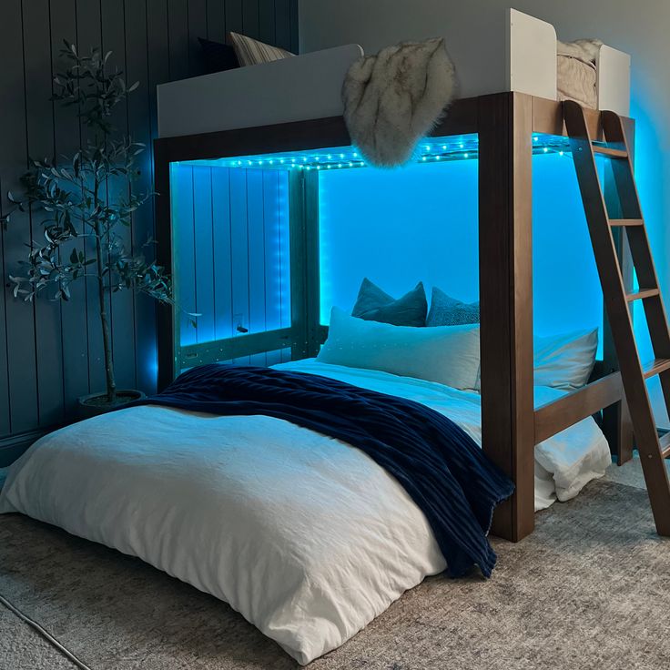 there is a bunk bed with blue lights in the room and white sheets on it