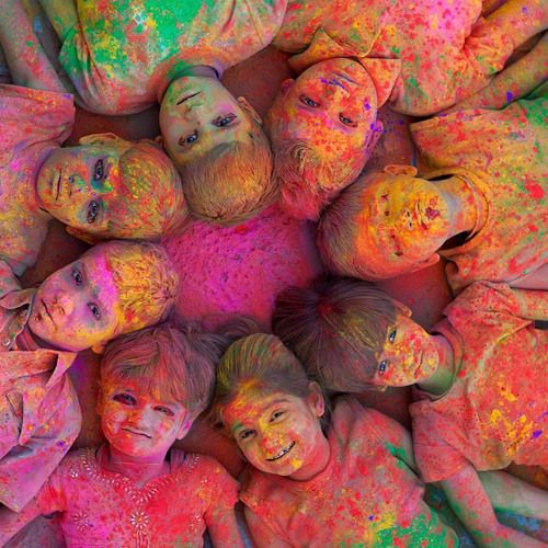 several children covered in colored powder laying on the ground