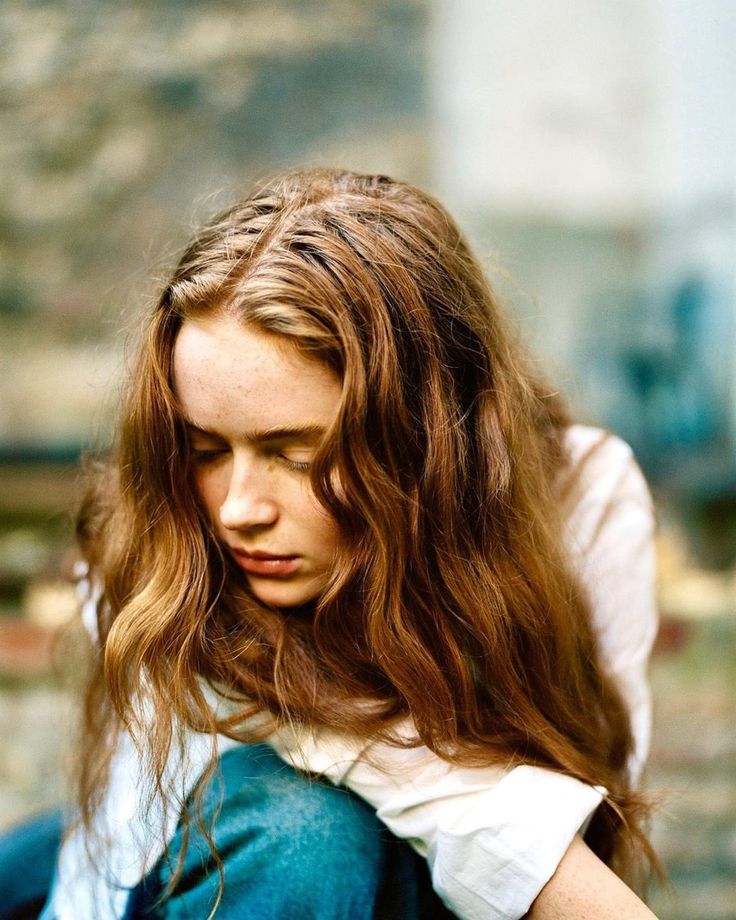 a woman with long hair sitting on the ground