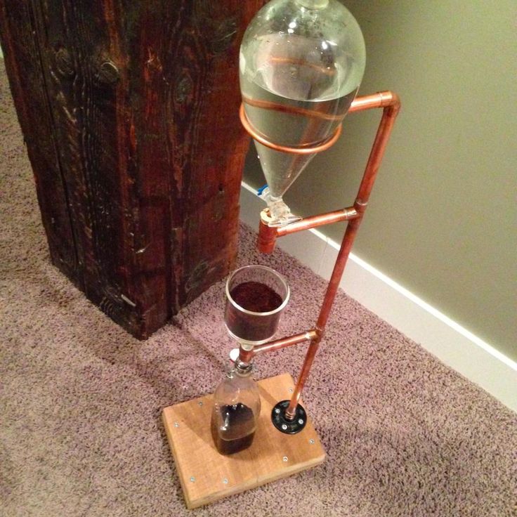 a glass filled with liquid sitting on top of a wooden stand next to a wall