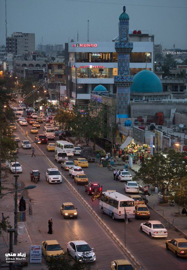 a city street filled with lots of traffic and tall buildings in the background at dusk