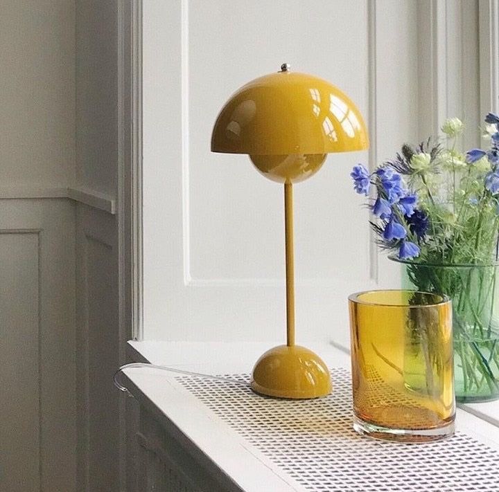 a yellow lamp sitting on top of a table next to a vase filled with flowers