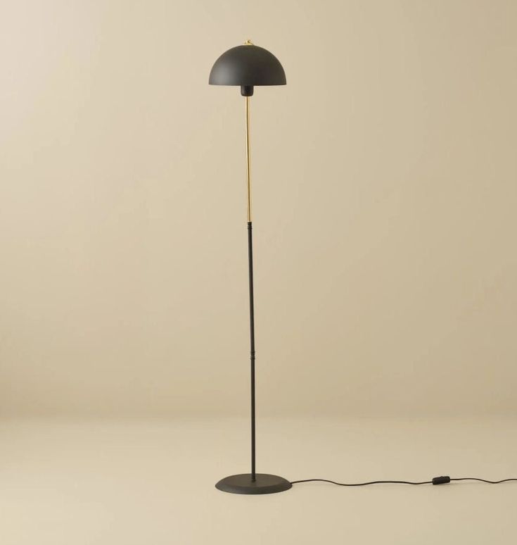 a floor lamp with a black shade on the base and a cord attached to it