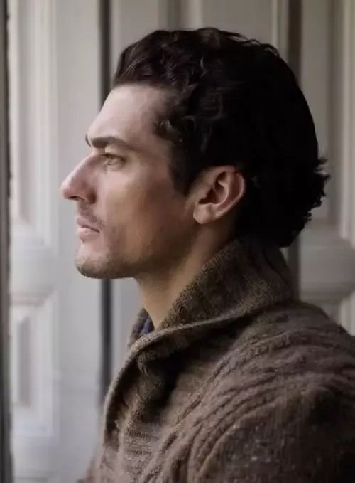 a man standing in front of a window with his head turned to the side and looking off